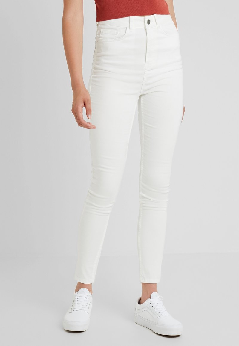 Vita högmidjade skinny jeans med en slät yta, med dragkedja, fem fickor och en smal passform. Bärs med vita sneakers.