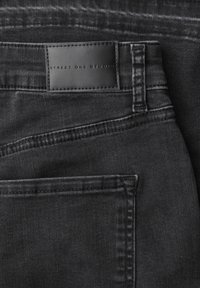 Jeans in denim nero con una trama liscia, dettagli di cuciture sottili e un'etichetta rettangolare in pelle impunturata con la scritta "Street One Studio".