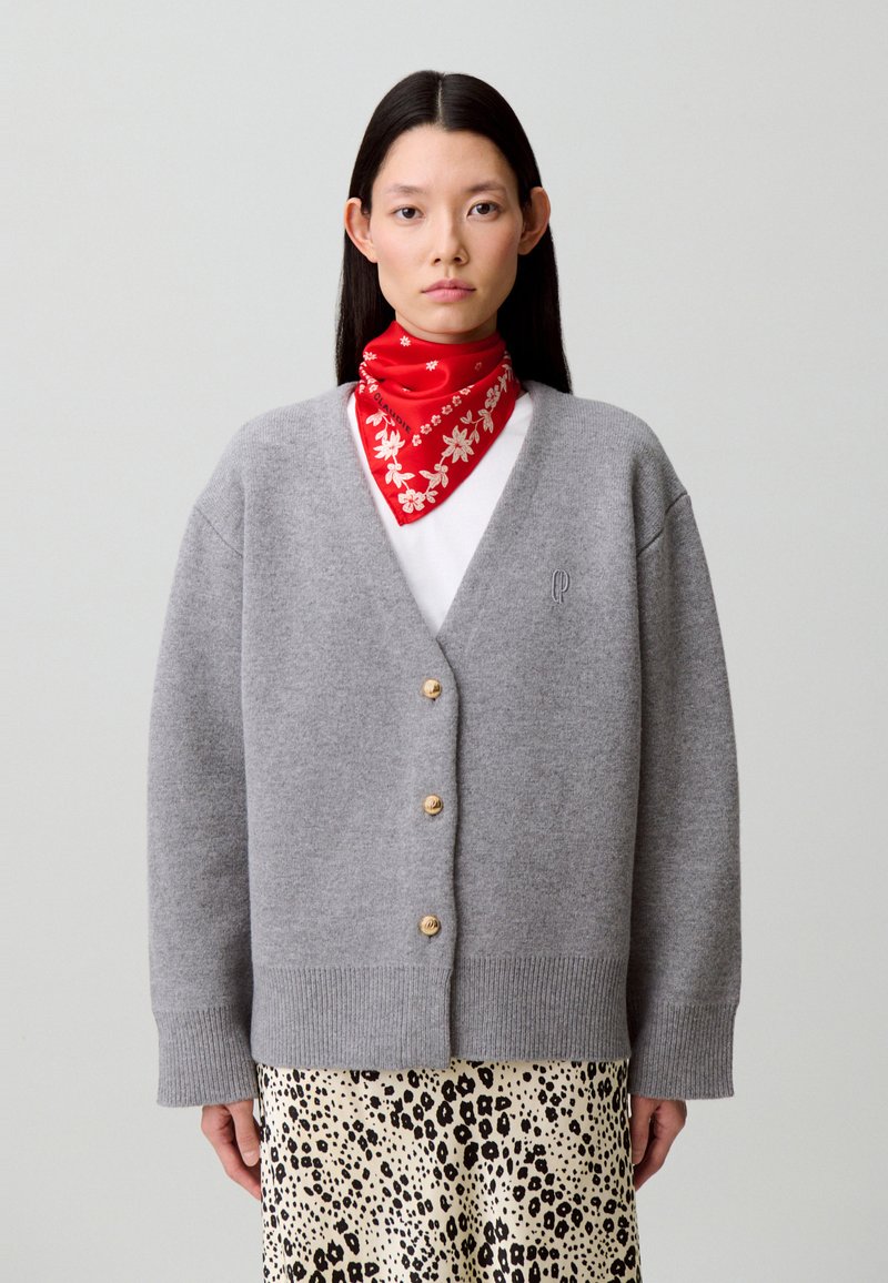 Cárdigan de lana gris con cuello en V, botones de madera y puños acanalados, combinado con una bufanda roja con estampado y una falda con estampado de leopardo.