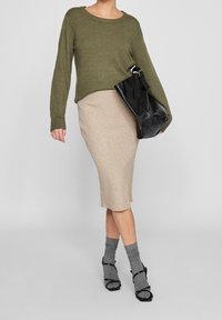 Stickad olivgrön tröja med ribbad textur, beige ribbad midkjol, grå lagerstrumpor och svart läderhandväska med silverdetaljer.