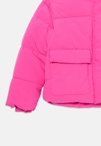 Manga de chaqueta acolchada de color rosa brillante con costuras acolchadas visibles y un gran bolsillo frontal con solapa sobre un fondo liso.