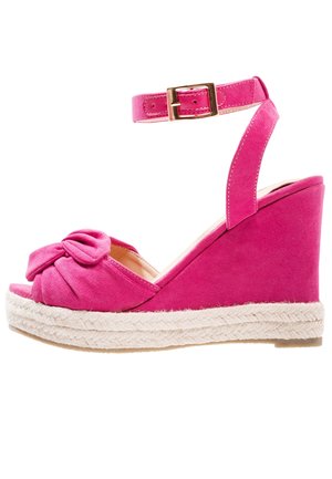 Lyserød ruskind kile sandal med ankremstrop, guldspænde, knude foran detalje og flettet espadrille platformsål.