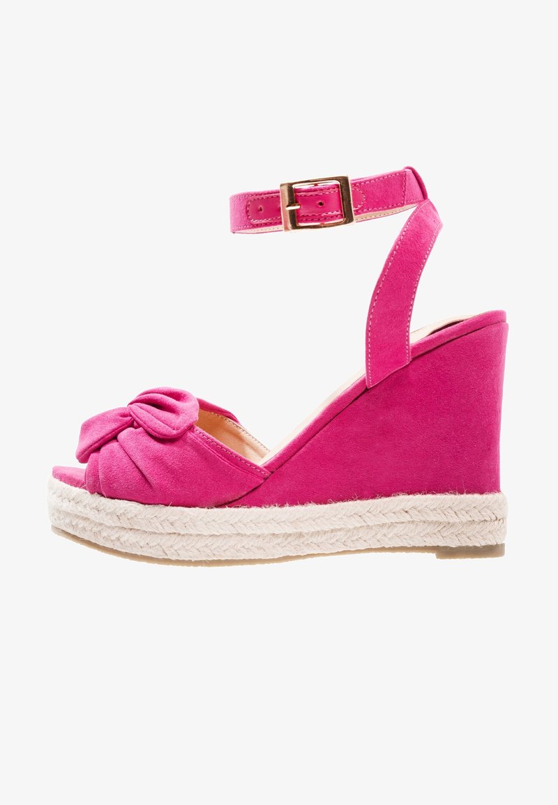 Sandale compensée en daim rose avec bride à la cheville, boucle dorée, détail noué à l'avant et semelle plate-forme en espadrille tissée.
