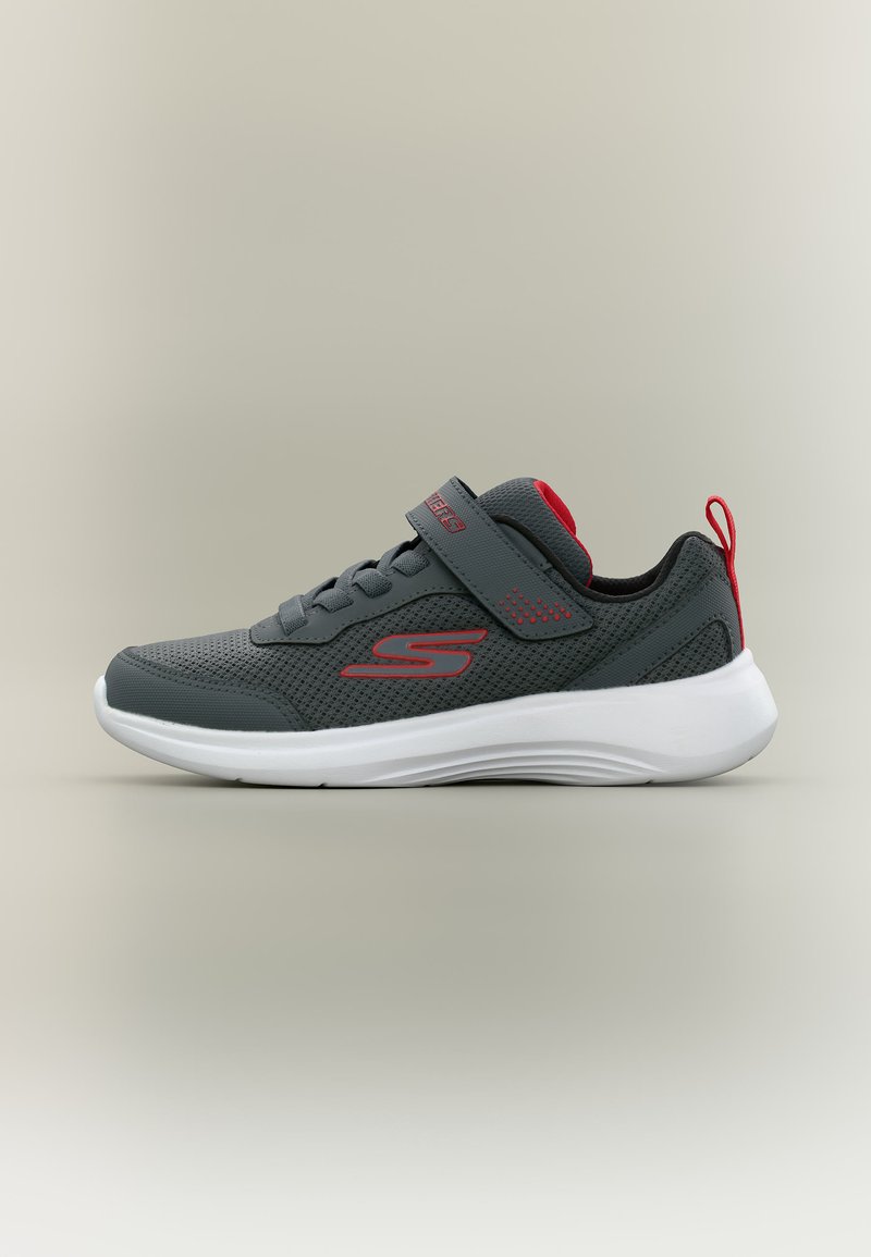 Baskets athlétiques gris foncé avec accents rouges, semelle blanche, empeigne en mesh, bride en Velcro et languette au talon, vues de côté.