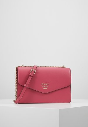 Bolso bandolera de cuero rosa DKNY con cadena dorada y correa ajustable de cuero con hebilla, colocado sobre una superficie blanca.