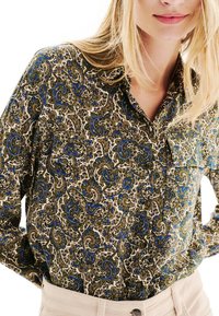 Chemise à manches longues présentant un motif paisley en vert, bleu et marron, confectionnée dans un tissu léger avec un col et une fermeture à boutons.