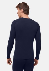 Mörkblå långärmad underställströja med figursydd design och sömlösa axlar, mjuk textur och klassisk rund halsringning. Perfekt för lager-på-lager.