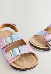 Glittriga sandaler med pastellfärgade rosa och blå remmar, kromade spännen, korkfotbädd och vitgummisula. Texturerad ovandel med glänsande partiklar.