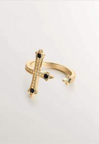 Anillo cruz de oro con un acabado brillante, que presenta acentos de piedra negra y una banda texturizada. El diseño incluye un detalle decorativo de perlas.