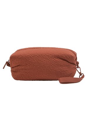 Pochette rectangulaire en tissu texturé couleur rouille avec fermeture zippée et sangle de poignet attachée sur fond blanc.