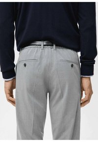 Gray tailored trousers with a smooth texture, side pockets, and a buttoned rear pocket. Worn with a dark sweater and visible black belt.