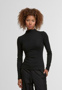 Čierny top s dlhým rukávom a vysokým golierom, vyrobený z hladkej látky. Priliehavý strih, jednoduchý siluet a minimalistický vzor.