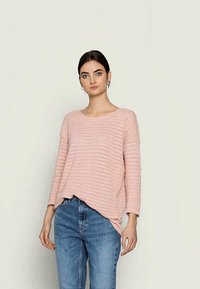 Suéter de malha rosa claro com riscas horizontais, decote redondo e mangas longas, combinado com jeans azuis de cintura alta.