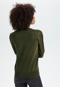 Olivgrüner Pullover mit strukturiertem Strick, geripptem Saum und Bündchen sowie leicht gepufften Ärmeln für zusätzlichen Schwung.