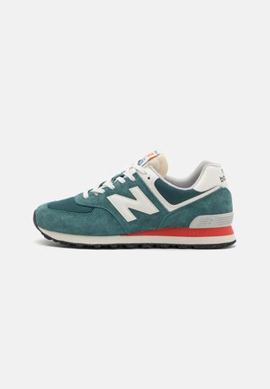 Teal suede and mesh sneaker with white accents, featuring a prominent 'N' logo, red sole detail, and a rounded toe design.