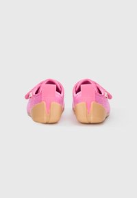 Pink fabric slip-on shoes with a textured upper, featuring a tan rubber sole and a rear pull tab for easy wear.