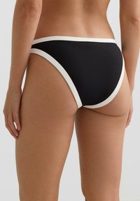 Czarne majtki od bikini z białym wykończeniem; posiadają wysoki krój na nogi oraz gładką fakturę tkaniny. Nadają się do noszenia na plaży lub przy basenie.