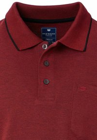 Burgunderfarbendes Poloshirt mit strukturiertem Gewebe, drei schwarzen Knöpfen, einer kleinen Tasche und einem kontrastierenden schwarzen Kragen. Das Etikett trägt die Aufschrift "Redmond Casual."