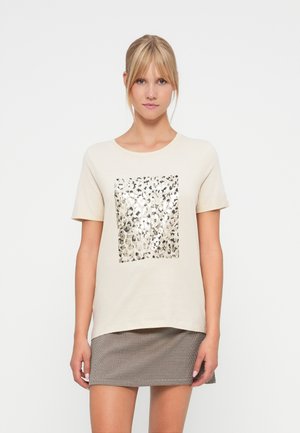 T-shirt en coton beige avec un design carré en imprimé léopard métallique au centre. Manches courtes et col rond, assorti à une jupe à carreaux.