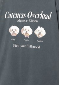 T-shirt gris avec trois illustrations de chiens maltais de différentes peluches, et le texte "Surcharge de Mignonnerie Édition Maltais" au-dessus.
