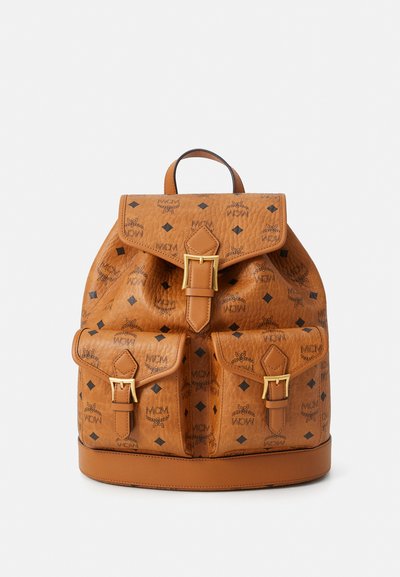 Sac à dos en cuir marron avec quincaillerie dorée, présentant un motif de logo, une fermeture à rabat, deux poches avant et une poignée supérieure.