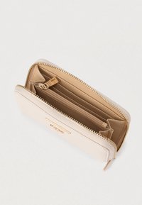 Portefeuille beige clair avec surface texturée, fermeture éclair dorée et plusieurs emplacements pour cartes. L'intérieur comprend une poche à pièces zippée et un détail logo.