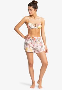 Bikini set se vzorem v květinovém designu s růžovými, žlutými a zelenými odstíny; obsahuje bralet top a odpovídající šortky se šňůrkou.