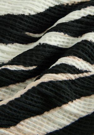 Tekstil ima črne in bež valovite črte na lahkem materialu. Tekstura se zdi rahlo gubana z mehko, zračnostjo.