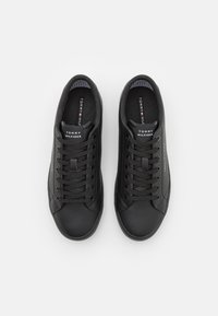 Para czarnych niskich sneakersów Tommy Hilfiger z sznurowadłami, logo na języku i wewnętrznej wkładce, ukazane z góry na białym tle.