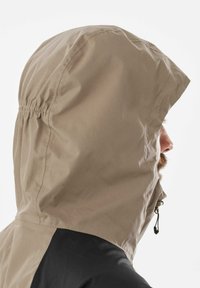 Beige Kapuzenjacke mit einem Kordelzug. Der untere Teil ist schwarz, mit einer glatten Textur und kontrastierenden Farben in einem schlichten Design.