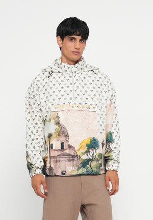Anorak bianco con motivo logo ripetuto, caratterizzato da un edificio illustrato e alberi colorati sul davanti. Polsini elasticizzati.