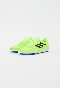 Zapatillas deportivas de color verde neón con rayas negras, tela texturizada, diseño con cordones y una suela blanca y azul, destacando la estética deportiva moderna.