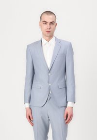 Chaqueta de traje azul claro con solapas con muescas y dos botones, combinada con una camisa blanca. Tejido suave con un ajuste a medida y bolsillos laterales.