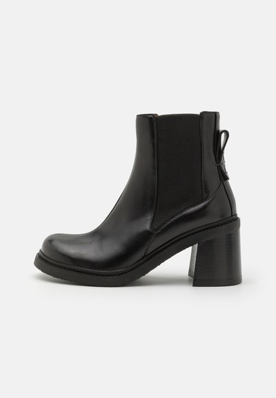 Bota de cuero negro hasta el tobillo con punta redondeada, paneles elásticos a los lados y un tacón grueso y apilado. Parte superior texturizada y detalle de tira para tirar.