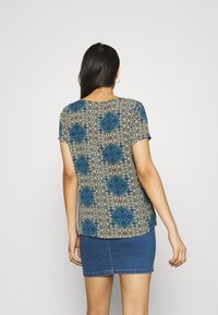 Short-sleeved blouse in lightweight fabric featuring a multicolored floral pattern on a beige background, paired with a denim skirt.