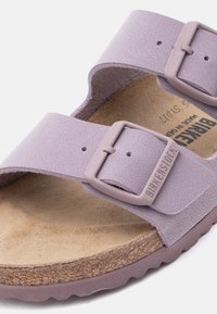 Σανδάλι Lilac Birkenstock με δύο ρυθμιζόμενα λουριά, ανάγλυφο λογότυπο στη πόρπη, πάτος από φελλό και υφή στην άκρη της σόλας.