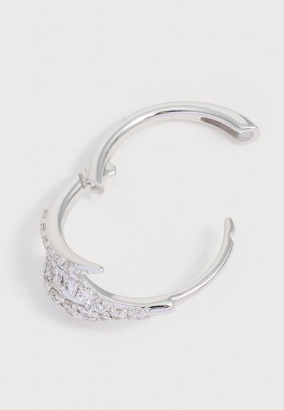 Boucle d'oreille créole en argent avec un fermoir ouvert, ornée d’un groupe de petites pierres précieuses claires et étincelantes sur un côté.
