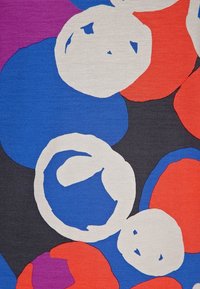 Motif abstrait avec de grands cercles irréguliers rouges, bleus, violets et blancs sur un fond gris foncé, rappelant un design de tissu moderne.