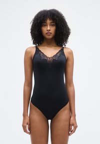 Μαύρο ολόσωμο μαγιό με δαντέλα γύρω από το V-λαιμόκοψη, λεπτές τιράντες και λείο, ελαστικό ύφασμα. Διαθέτει ψηλό κόψιμο στο πόδι.