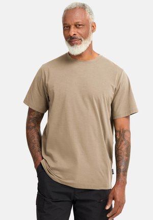 Hellbraunes Baumwoll-T-Shirt mit kurzen Ärmeln, Rundhalsausschnitt und geradem Saum. Zeigt sichtbare Tätowierungen auf den Unterarmen.