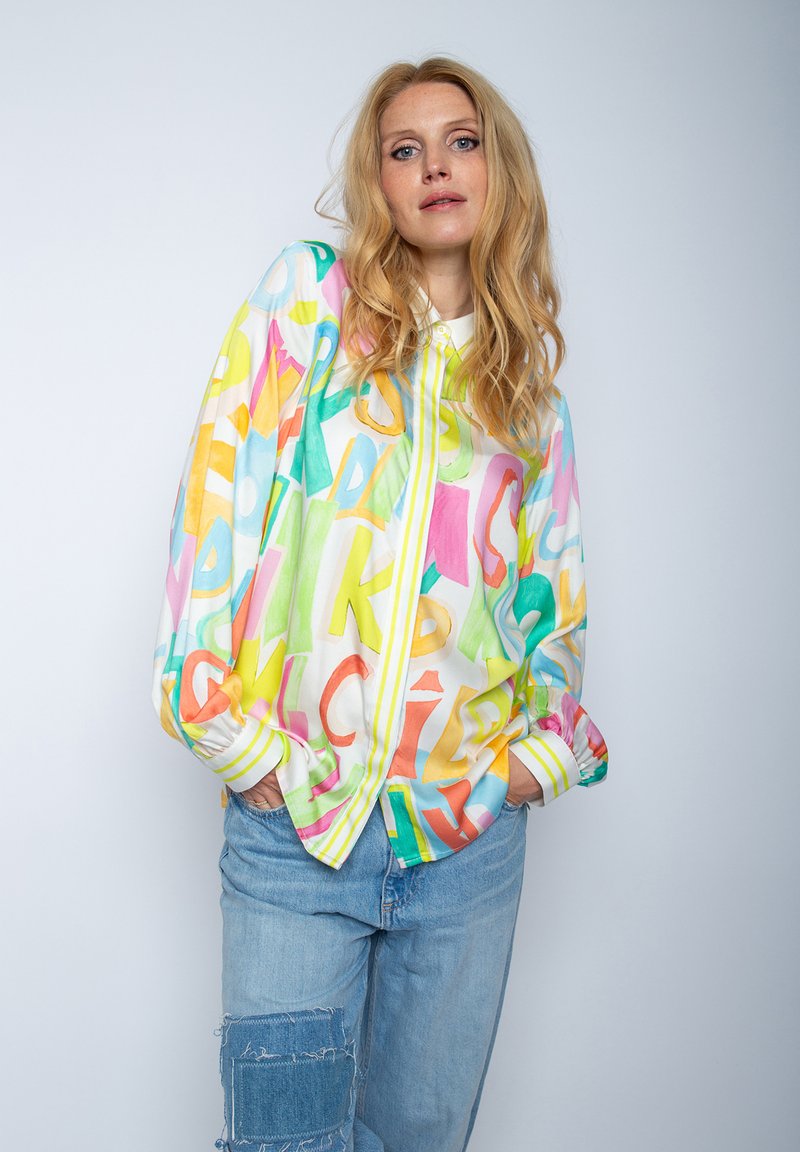 Bunte, leichte Hemdjacke mit großen, abstrakten Buchstaben in Pink, Gelb und Grün auf weißem Hintergrund; lässige Passform der Ärmel.