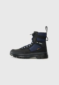 Bottines noires et bleues avec une tige en tissu texturé, fermeture à lacets, bout renforcé et semelle en caoutchouc. Coutures contrastées et tirette.
