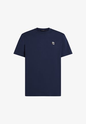 Marineblaue T-Shirt mit kurzen Ärmeln und Rundhalsausschnitt, mit kleinem weißen und schwarzen Logo-Patch auf der linken Brust.