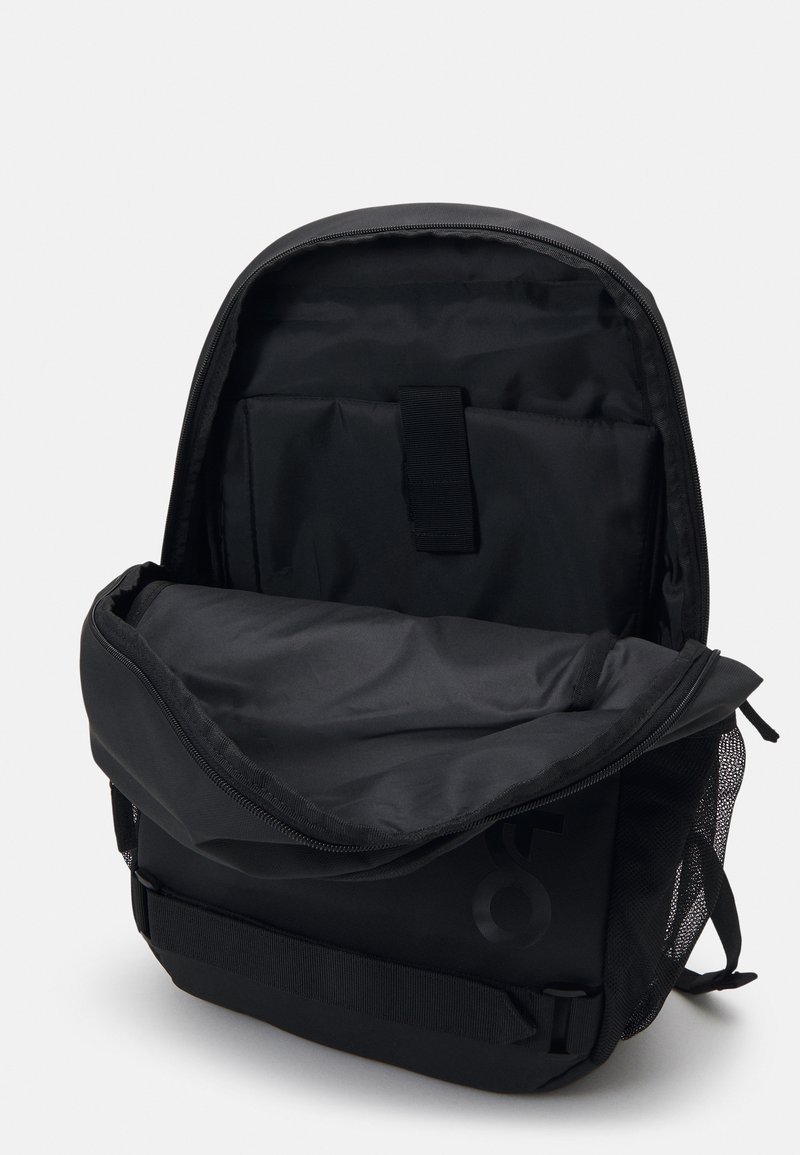 Black backpack with a textured surface, zip closure, and adjustable straps. Features an interior compartment for organization and a mesh side pocket.