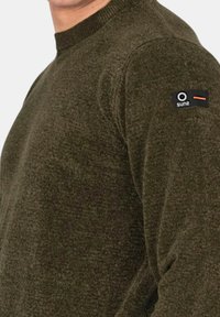 Maglione verde oliva in maglia con collo rotondo, caratterizzato da una finitura testurizzata e una toppa con logo sulla spalla sinistra.