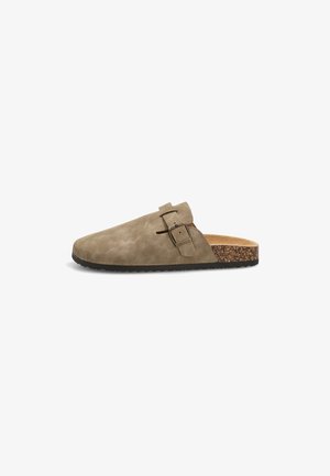 Zueco marrón sin cordones con parte superior de ante, hebilla lateral ajustable, plantilla de corcho y suela negra texturizada.