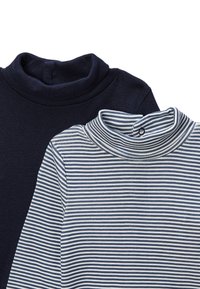 Deux hauts à col roulé : un uni bleu marine, l'autre blanc avec des rayures bleu marine. Les deux ont une coupe ajustée et une texture en coton doux.