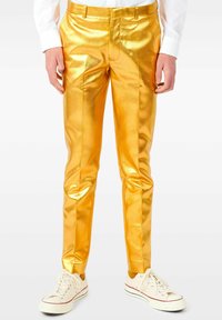 Pantaloni dorati lucidi con una vestibilità slim, caratterizzati da una texture liscia, fronte piatto e passanti per cintura, abbinati a sneakers in tela bianche.
