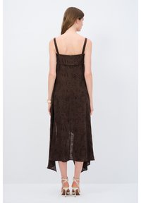 Vestito marrone con motivo floreale, cerniera sul retro, spalline sottili e orlo fluente. Realizzato in tessuto leggero.