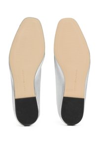 Chaussures à talon moyen argentées avec une tige métallique lisse et une semelle en caoutchouc noir contrastante. Présente un logo en relief sur la semelle intérieure.